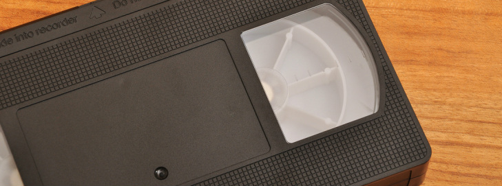 A classic VHS video tape up close showing black plastic casing and white tape spools.