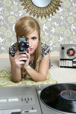 Vintage 1965 girl in room with Super8 film camera, reel to reel and LP player.
