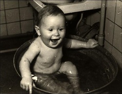 OLd black and white of baby in baby in tin bath tub.